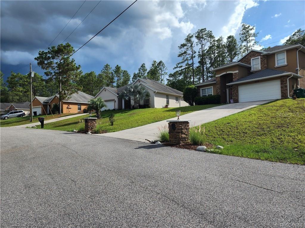 A street view of three suburban houses with driveways and lawns under a cloudy sky — 11107 N MATARO AVENUE, CITRUS SPRINGS, FL