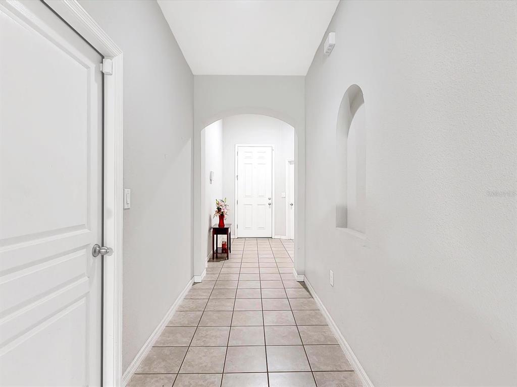 A tiled hallway features an arched entryway, a wall niche, and a white door — 955 LA MIRADA COURT, KISSIMMEE, FL