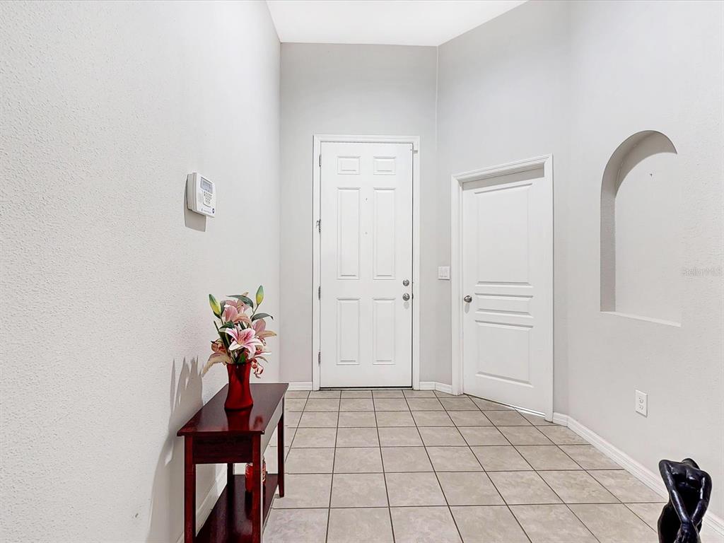 An entryway features light-colored tile flooring, a white front door, and a small wooden table — 955 LA MIRADA COURT, KISSIMMEE, FL