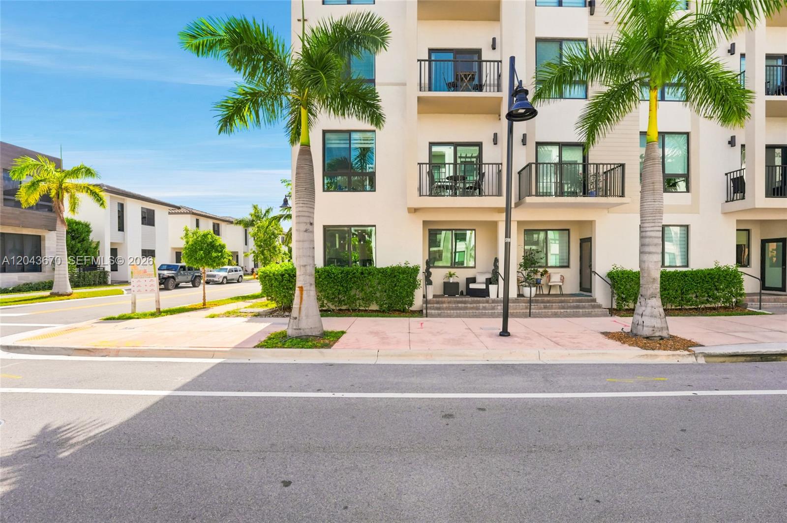 The exterior of a multi-story residential building features balconies, palm trees, and a sidewalk — 8167 NW 41st St # 101, Doral FL 33166, DORAL, FL