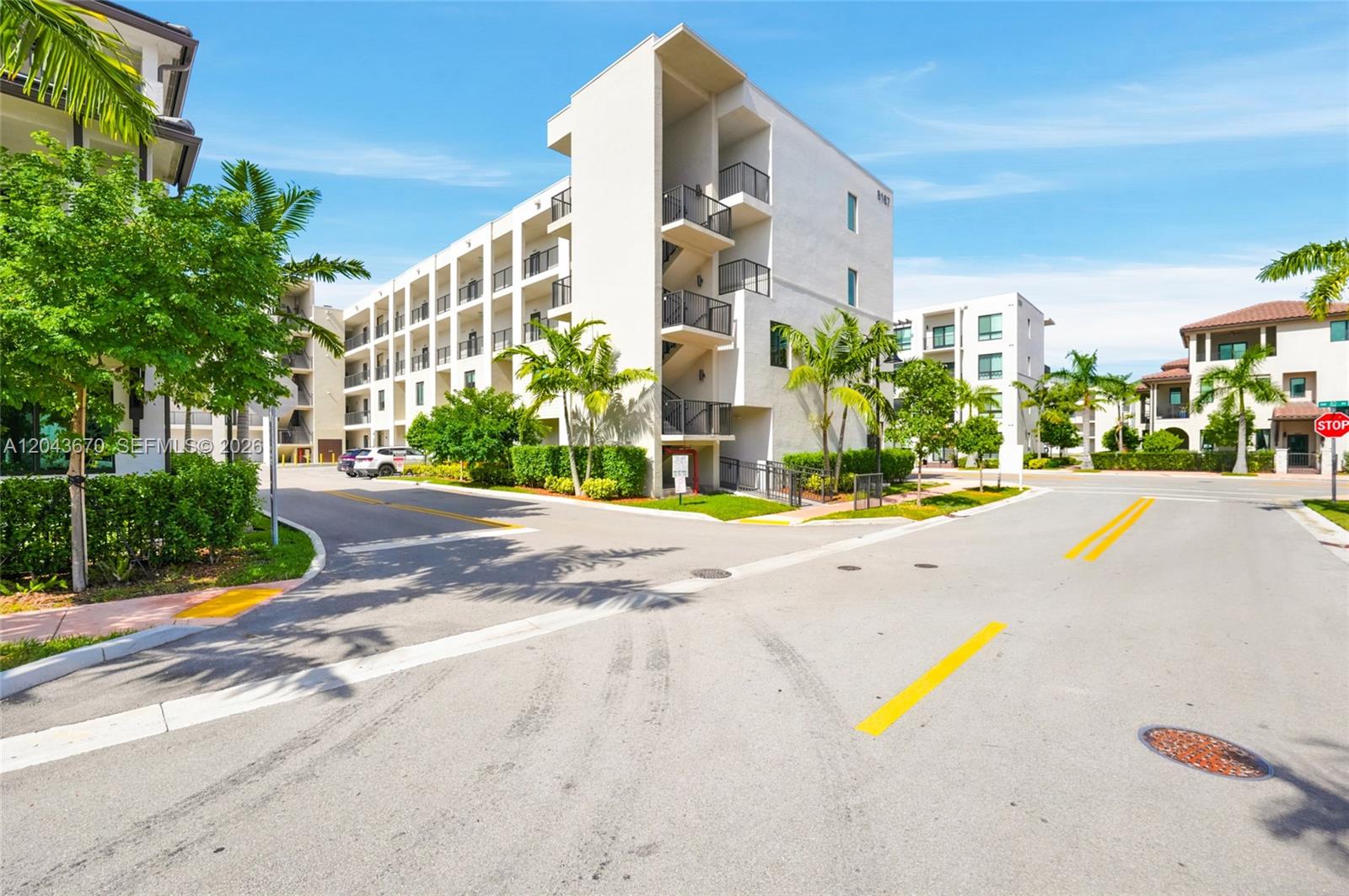 A multi-story apartment building with exterior staircases stands near a paved road and palm trees — 8167 NW 41st St # 101, Doral FL 33166, DORAL, FL