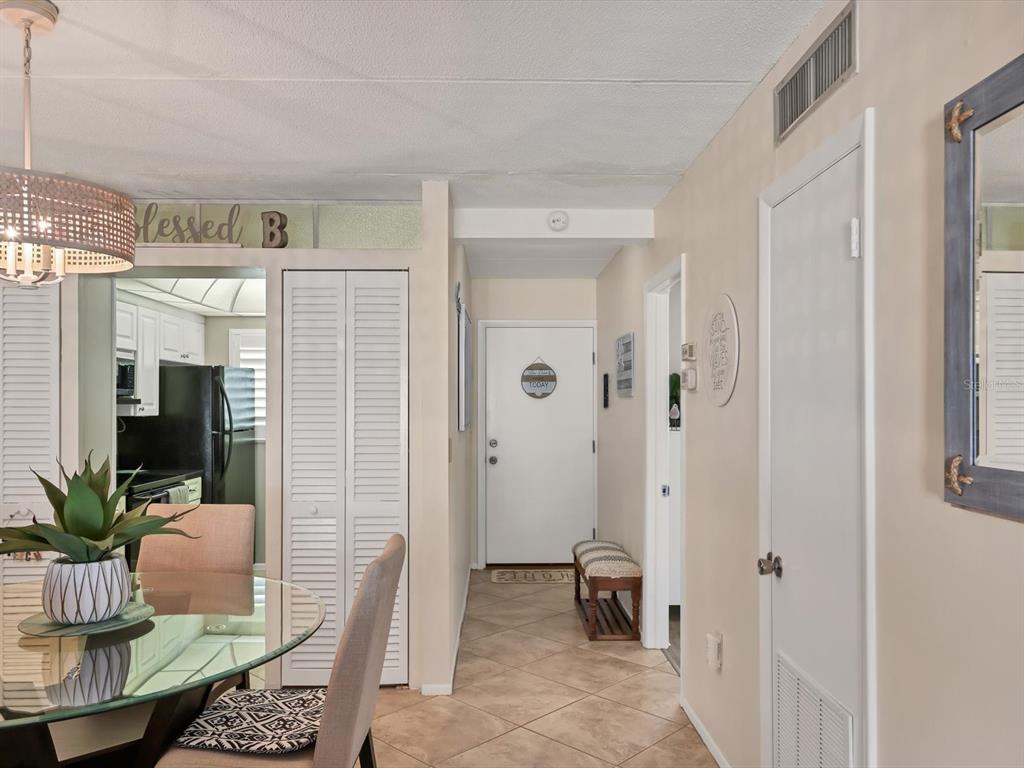 A dining area with a glass table leads into a hallway with a white door — 708 TAMIAMI TRAIL S UNIT 105, VENICE, FL