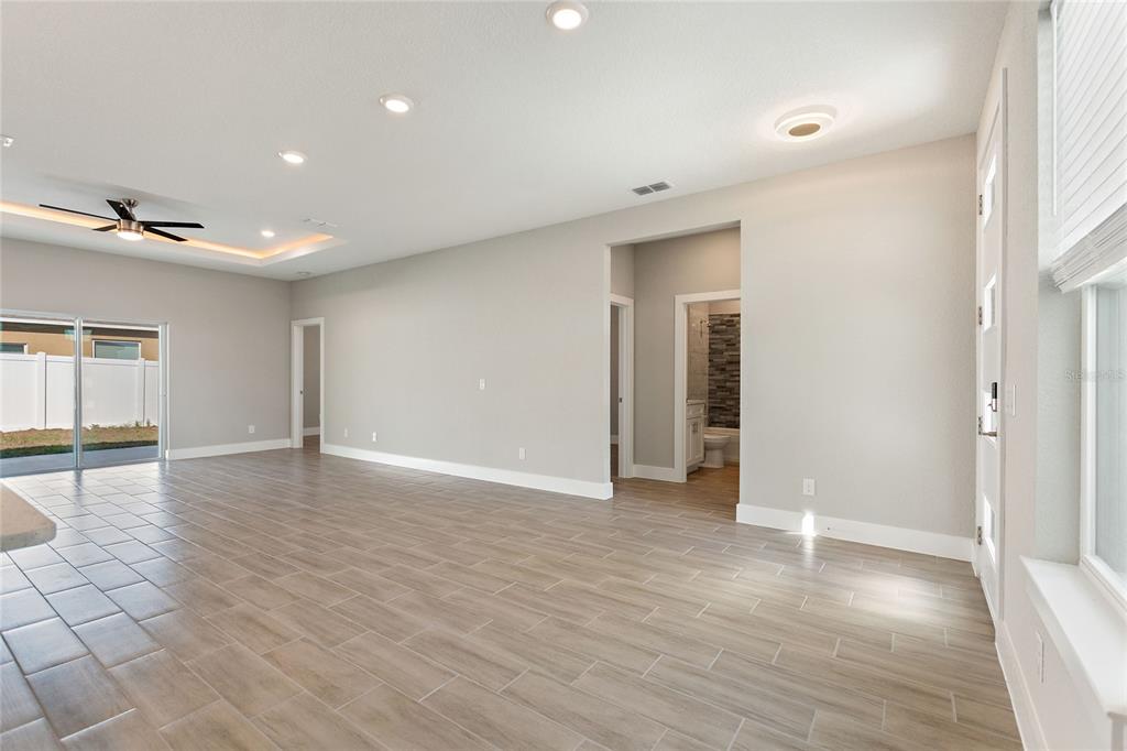 A bright living area features light wood-look tile flooring, recessed lighting, and a ceiling fan — 802 JAMES DRIVE, POINCIANA, FL