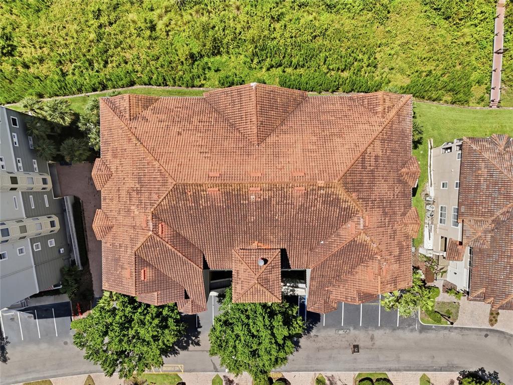 An aerial view shows the brown tiled roof of a multi-story building with surrounding landscaping — 8767 THE ESPLANADE UNIT 40, ORLANDO, FL
