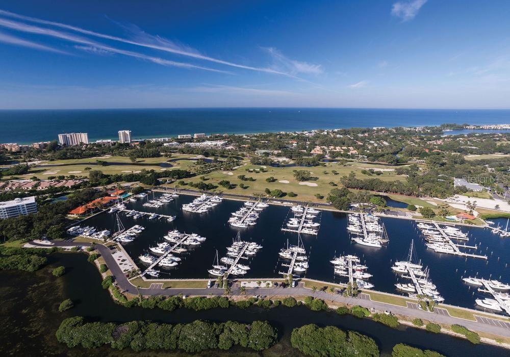 An aerial view of a marina with many docked boats next to a golf course — 2600 HARBOURSIDE DRIVE UNIT J-04, LONGBOAT KEY, FL