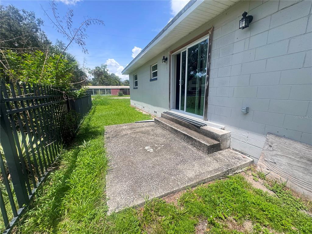 A concrete patio sits outside a house with a sliding glass door and block walls — 1700 S OLEANDER AVENUE, SANFORD, FL