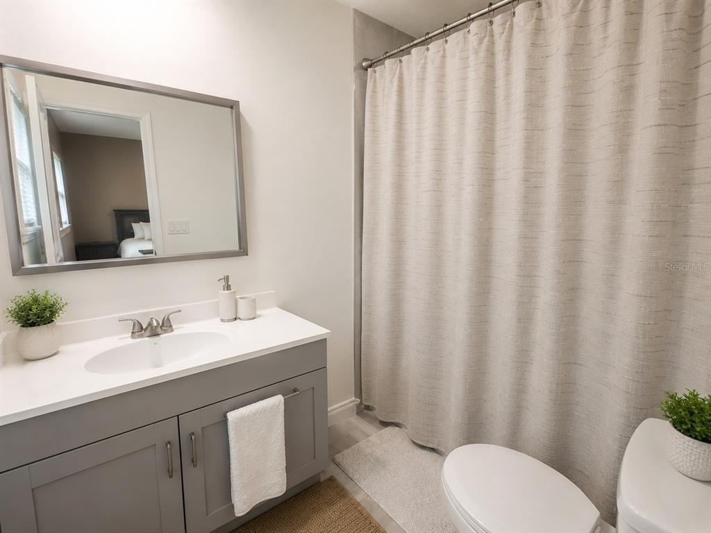 A bathroom features a gray vanity, a white countertop, and a beige shower curtain — 1700 S OLEANDER AVENUE, SANFORD, FL