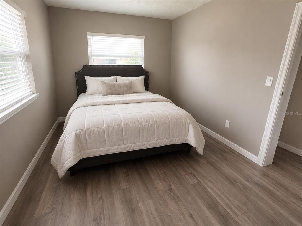 A bedroom features a bed with a dark headboard, light bedding, and wood-look flooring — 1700 S OLEANDER AVENUE, SANFORD, FL