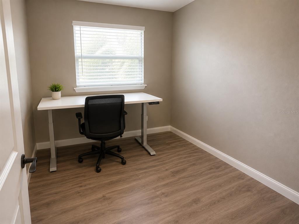 A home office features a white standing desk, a black chair, and wood-look flooring — 1700 S OLEANDER AVENUE, SANFORD, FL