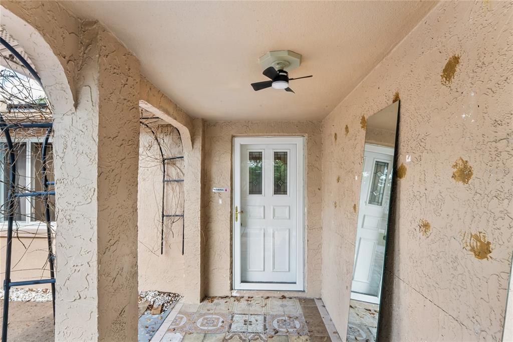 A covered entryway features a white front door, a ceiling fan, and a floor mirror — 3122 BAHIA AVENUE, HOLIDAY, FL