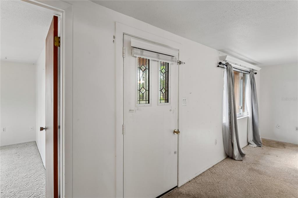 A room with white walls, beige carpet, a white door, and a window with curtains — 3122 BAHIA AVENUE, HOLIDAY, FL