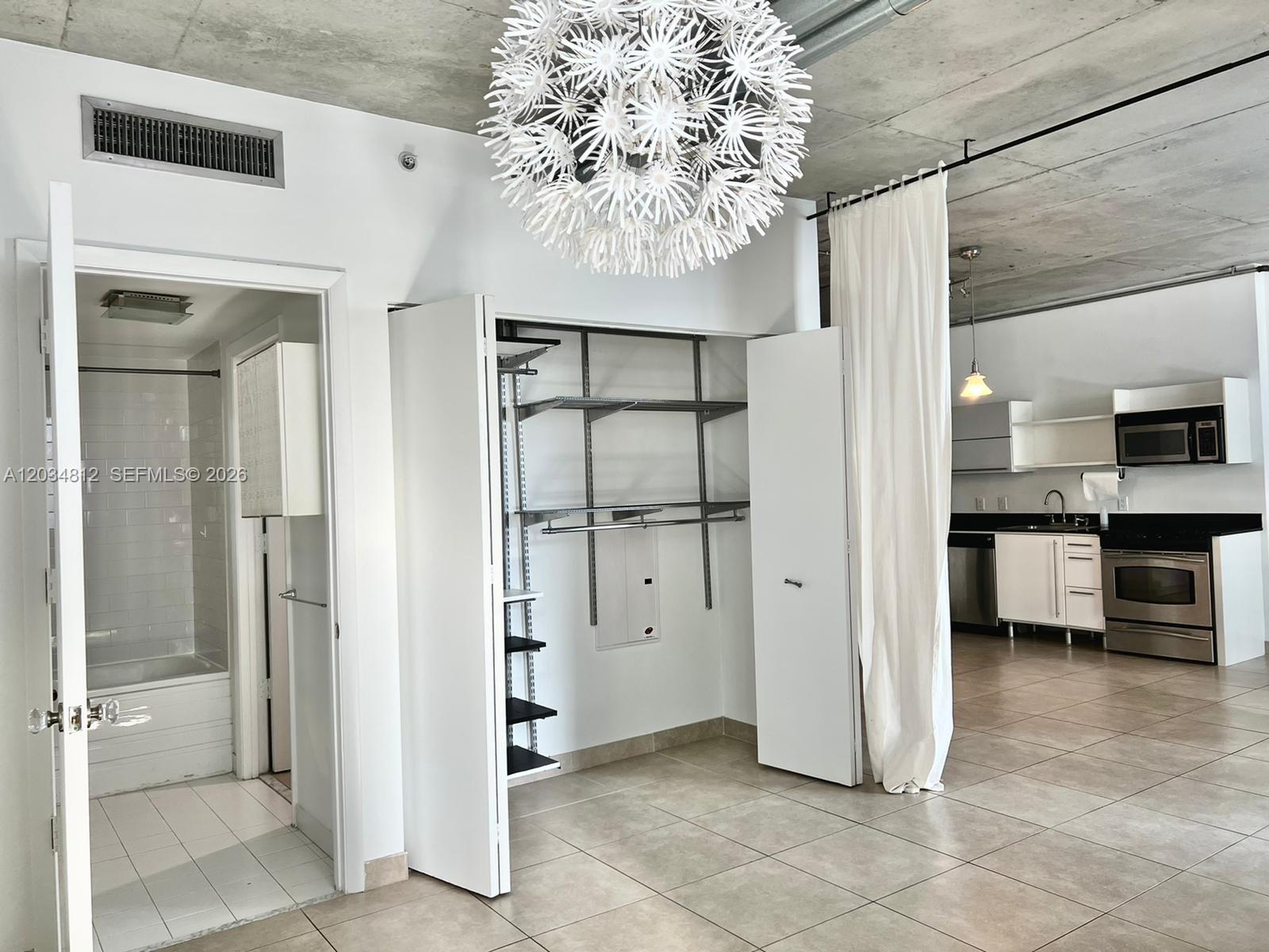 An open-concept interior features a bathroom, a closet with shelving, and a kitchen area — 690 SW 1st Ct # 1026, Miami FL 33130, MIAMI, FL