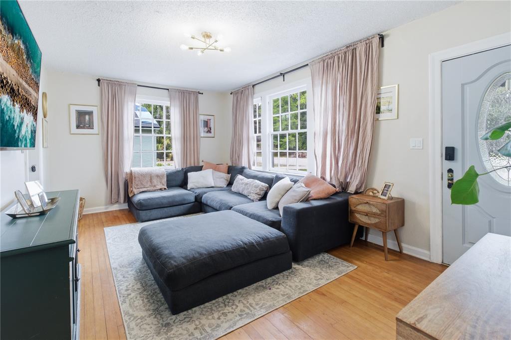 A living room features a dark gray sectional sofa, hardwood floors, and large windows — 4224 REDWOOD AVENUE, JACKSONVILLE, FL