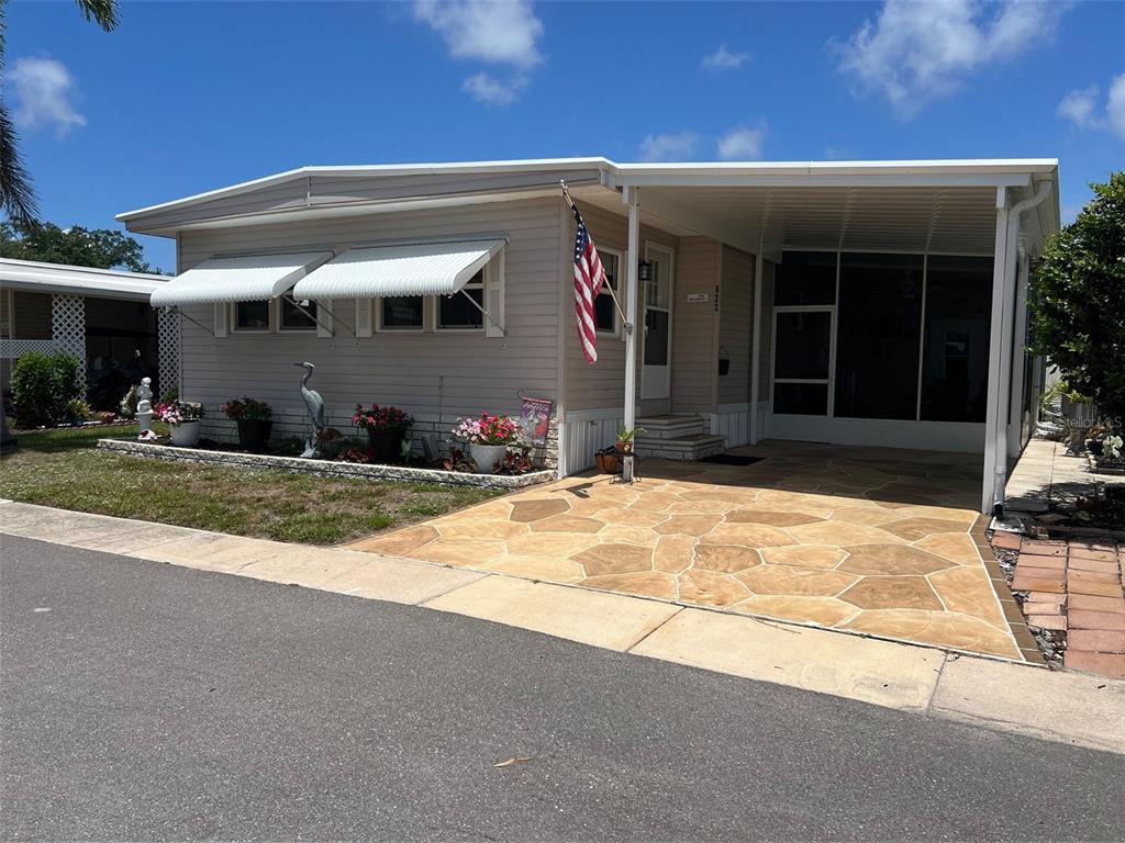 A single-story manufactured home features light siding, a carport, and a stone-patterned driveway — 29250 US HIGHWAY 19 N UNIT 622, CLEARWATER, FL