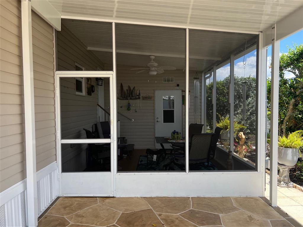 A screened-in porch with a white door, ceiling fan, and stone-patterned patio flooring — 29250 US HIGHWAY 19 N UNIT 622, CLEARWATER, FL
