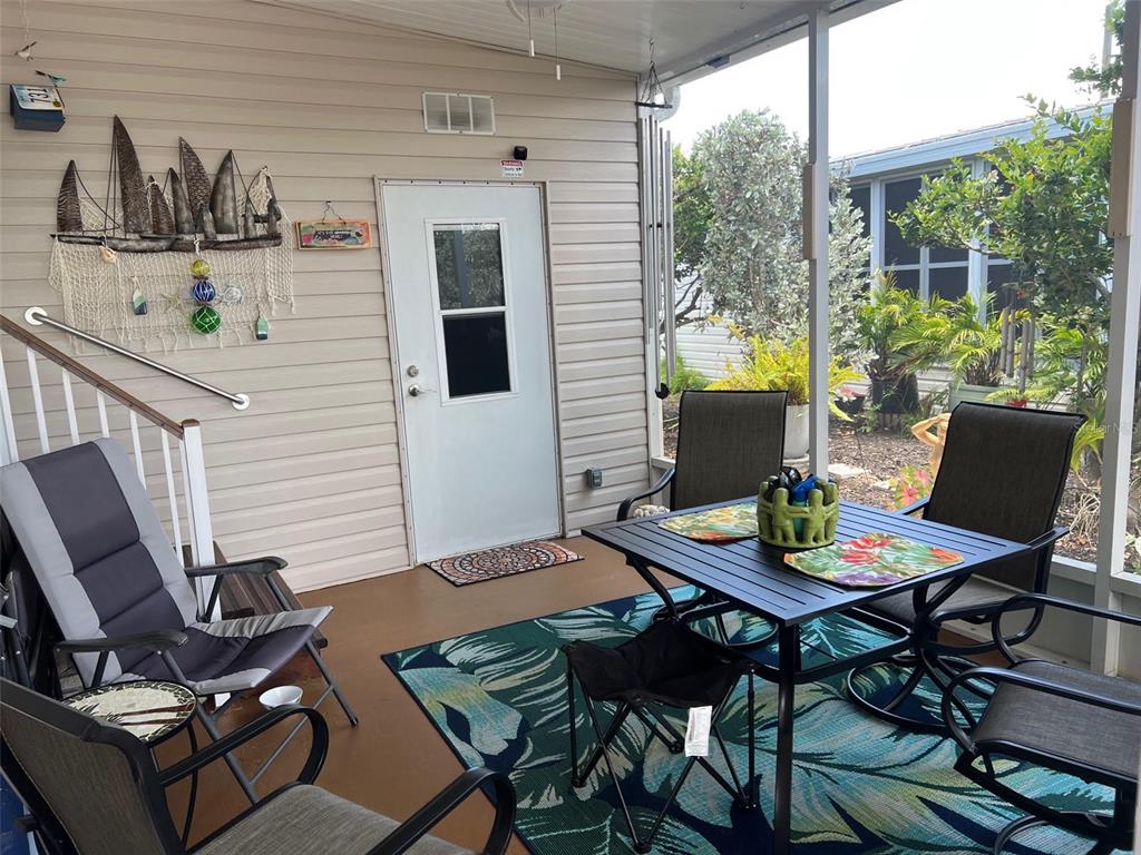 A screened-in porch features a dining set, a lounge chair, and a white entry door — 29250 US HIGHWAY 19 N UNIT 622, CLEARWATER, FL