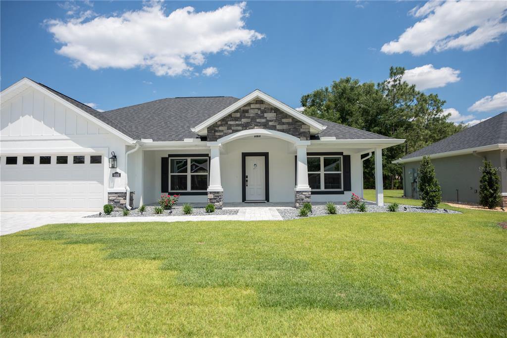 A single-story house with a white exterior, stone accents, and a covered front porch — 6689 SW 179TH COURT ROAD, DUNNELLON, FL
