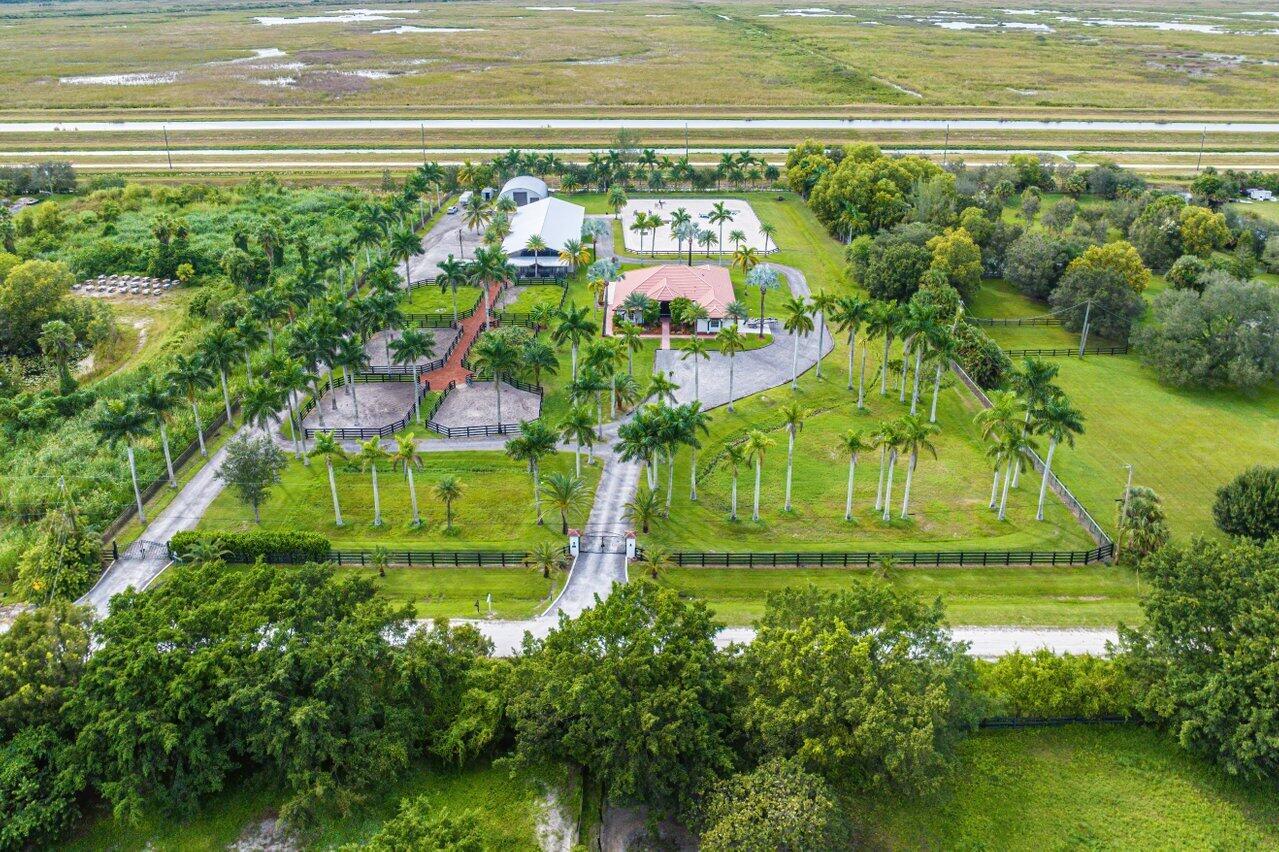 An aerial view shows a house with a barn, horse paddocks, and palm trees — 2587 Skipiks Way, Wellington FL 33470, WELLINGTON, FL