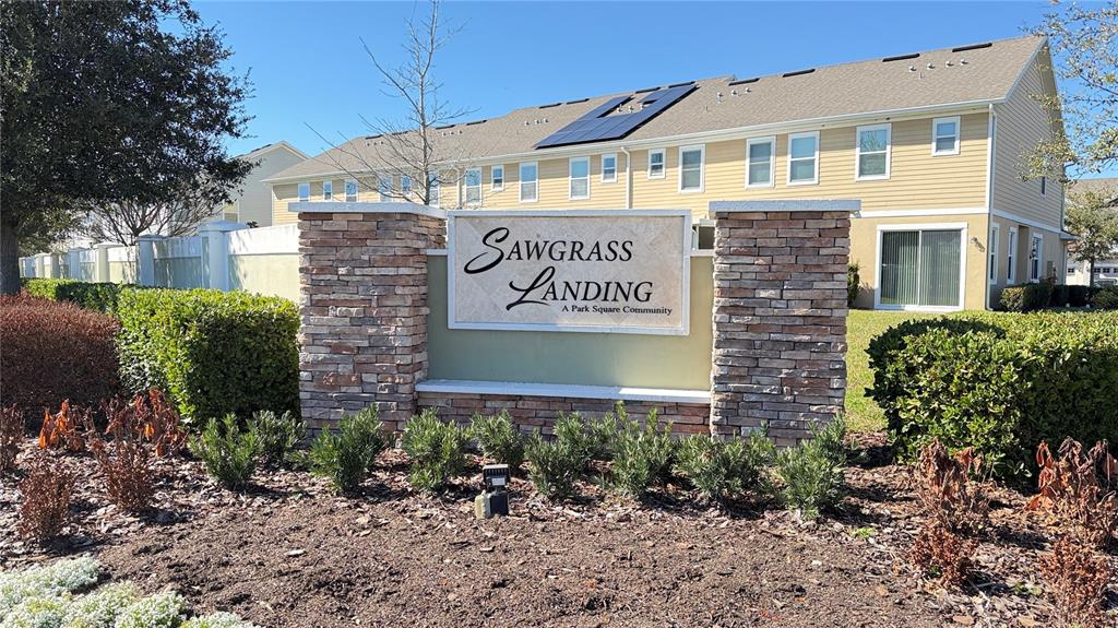 A stone monument sign for Sawgrass Landing stands in front of a yellow multi-family building — 2636 SEDGE GRASS WAY, ORLANDO, FL