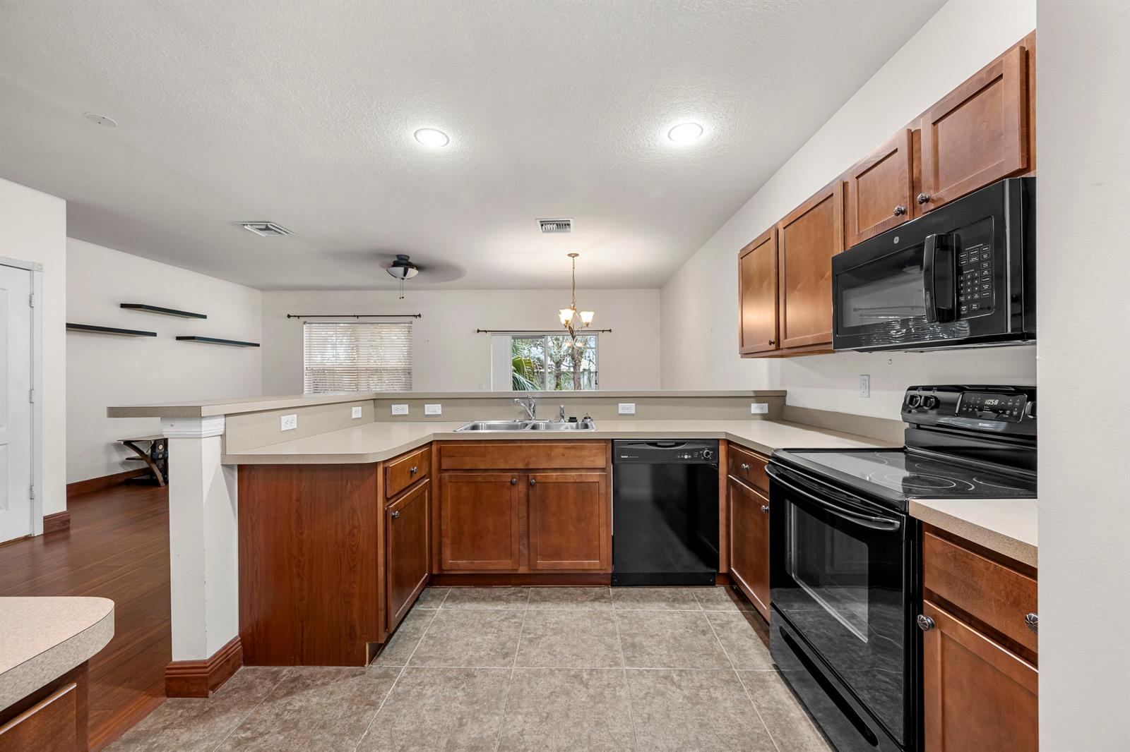 A kitchen features wood cabinets, black appliances, tan countertops, and tile flooring — 2545 Creekside Drive, Fort Pierce FL 34981, FORT PIERCE, FL