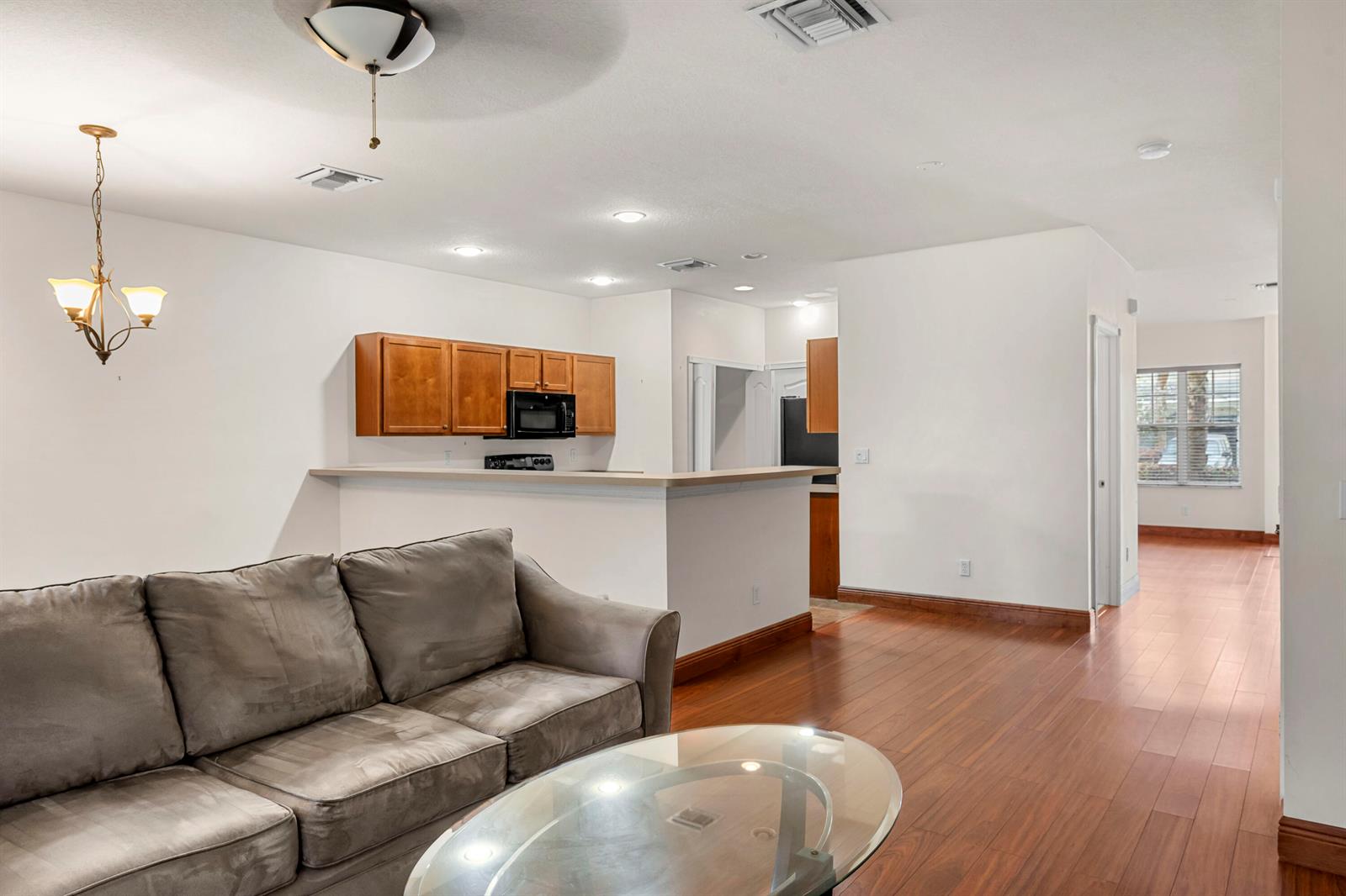 A living room with a grey sofa and glass coffee table opens to a kitchen — 2545 Creekside Drive, Fort Pierce FL 34981, FORT PIERCE, FL