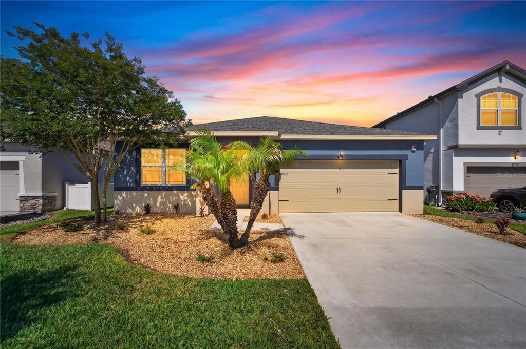 A single-story house with a blue exterior, a two-car garage, and a palm tree — 13517 TEXAS SAGE PLACE, RIVERVIEW, FL