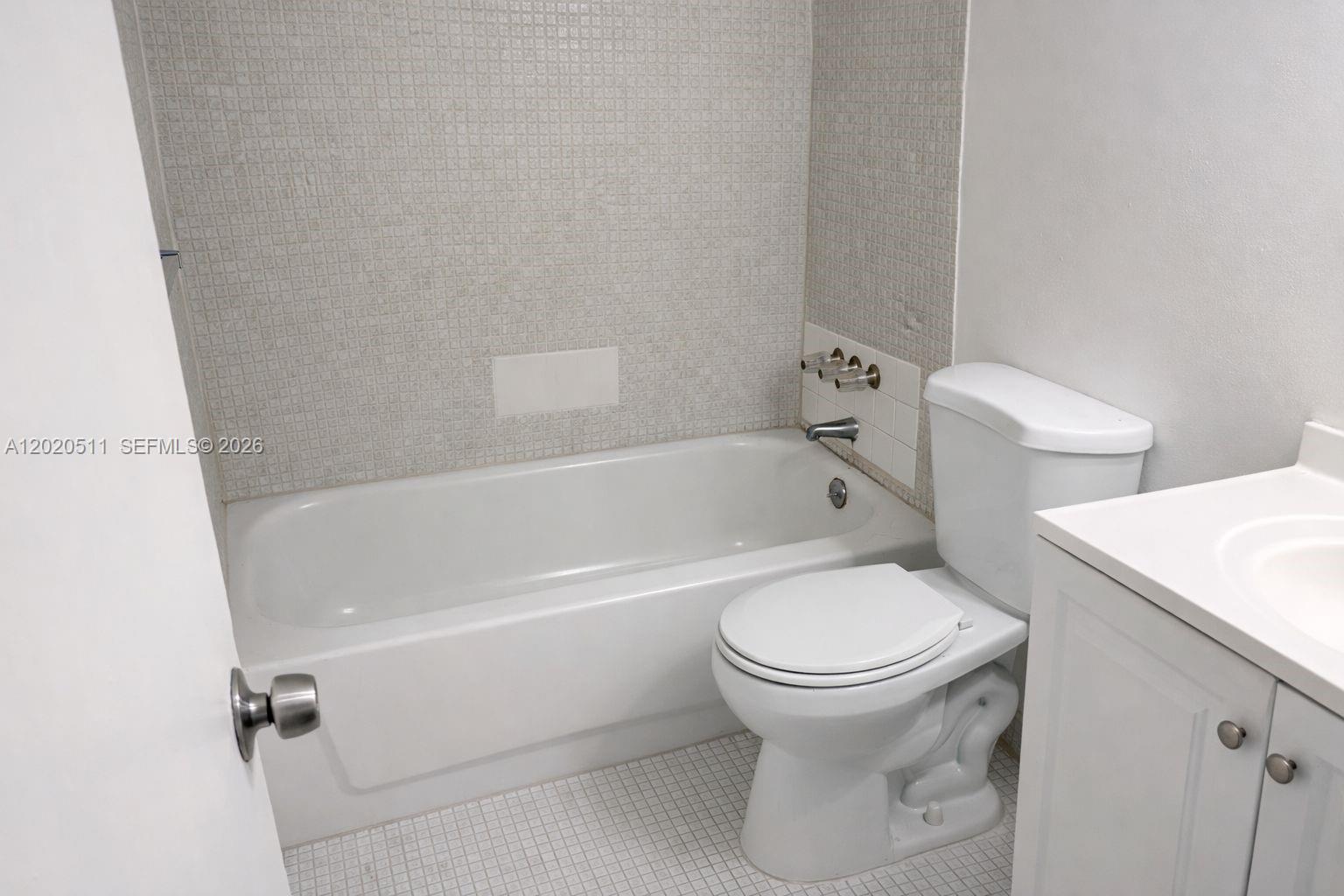 A bathroom features a white bathtub, a toilet, and a vanity with a white countertop — 496 NW 165th # 412, Miami FL 33169, MIAMI, FL