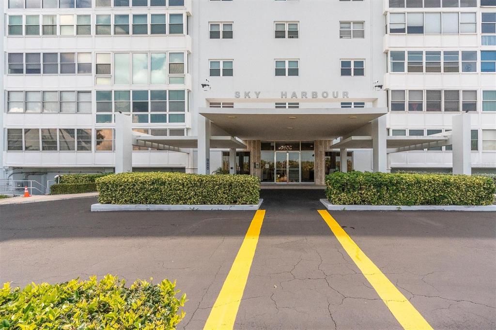 The exterior of a multi-story apartment building features a covered entrance with yellow painted lines — 7200 SUNSHINE SKYWAY LN S UNIT 15H, ST PETERSBURG, FL