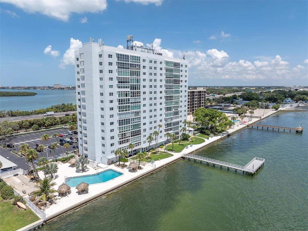 An aerial view of a tall white apartment building with a pool and a pier — 7200 SUNSHINE SKYWAY LN S UNIT 15H, ST PETERSBURG, FL