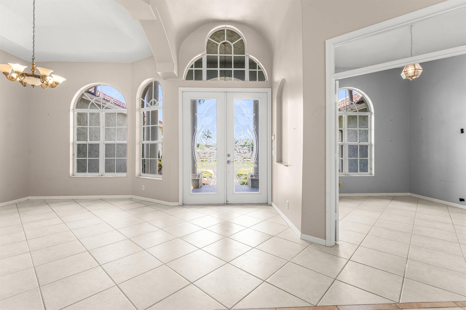 An entryway with tiled floors, double glass doors, and arched windows leads into a room — 19482 Green Grove Court, FL 33470, FL