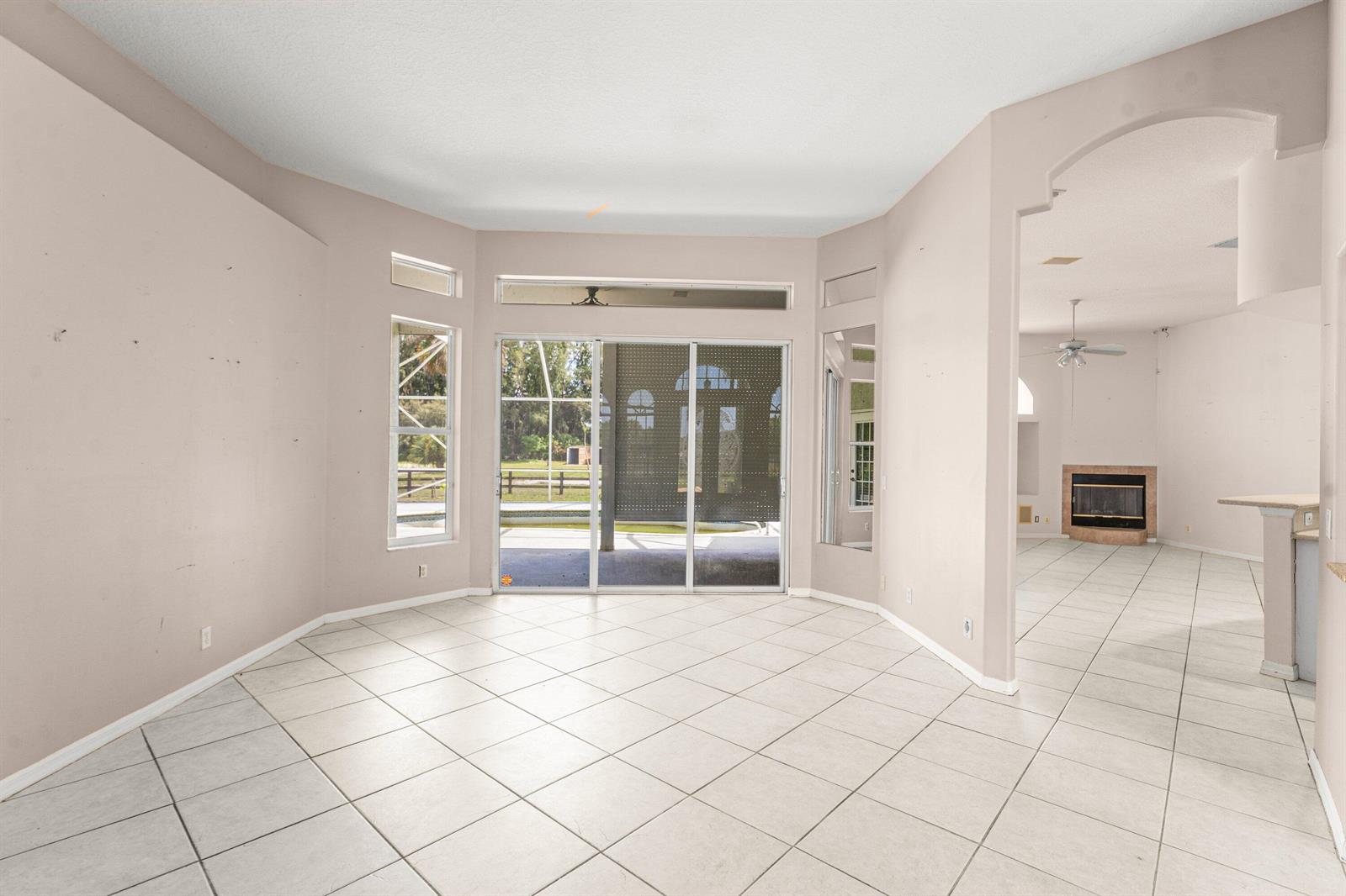 A tiled living area with sliding glass doors leading to a screened-in patio and pool — 19482 Green Grove Court, FL 33470, FL