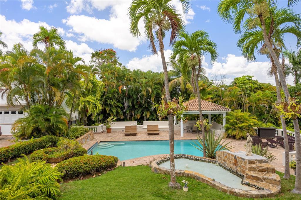 A swimming pool with a stone fountain and a gazebo in a lush tropical backyard — A Street VILLA CAPARRA UNIT A-13, GUAYNABO, PR