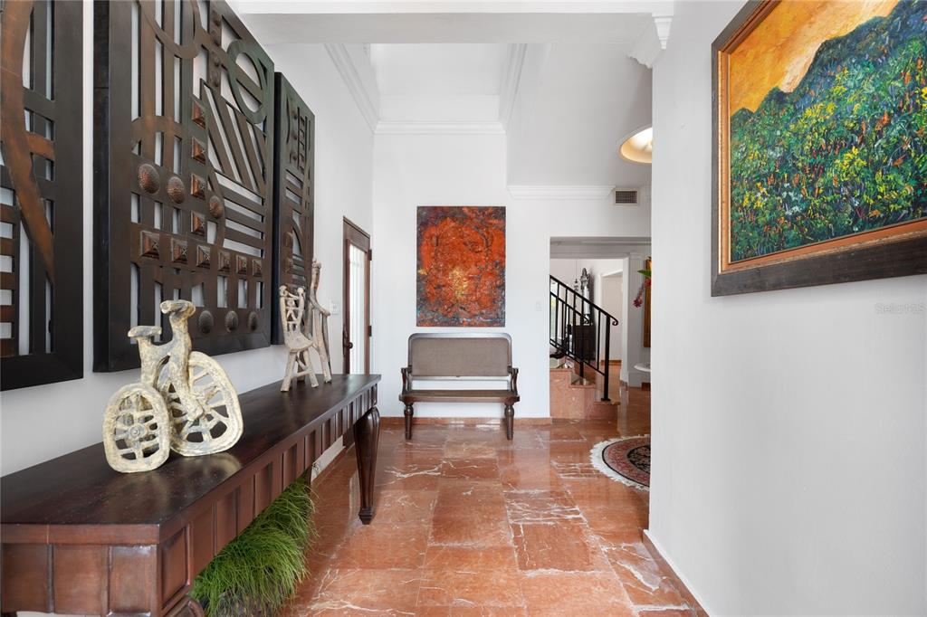 A foyer with red marble flooring, a wooden console table, and abstract wall art — A Street VILLA CAPARRA UNIT A-13, GUAYNABO, PR