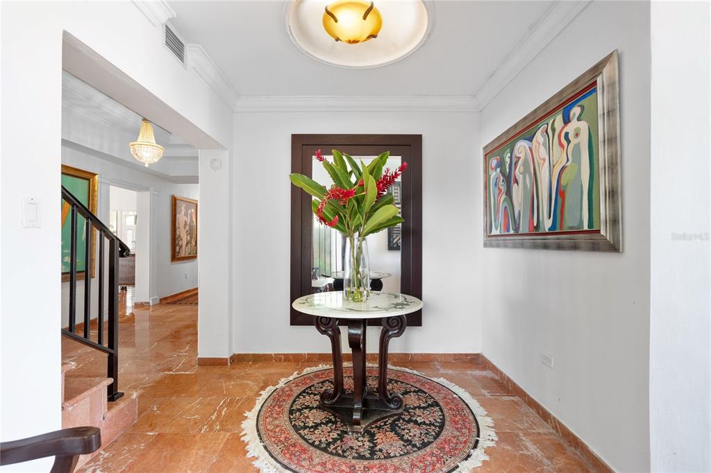 A foyer features a marble-topped pedestal table, a round rug, and a large wall mirror — A Street VILLA CAPARRA UNIT A-13, GUAYNABO, PR