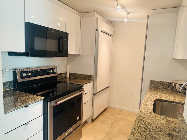 A kitchen features white cabinetry, granite countertops, a stainless steel stove, and a white refrigerator — 10275 Collins Ave # 223, Bal Harbour FL 33154, BAL HARBOUR, FL