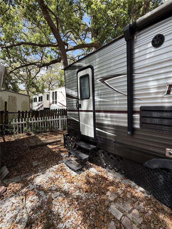 The exterior of a travel trailer is parked on a gravel lot with trees nearby — 3000 CLARCONA ROAD UNIT 743, APOPKA, FL