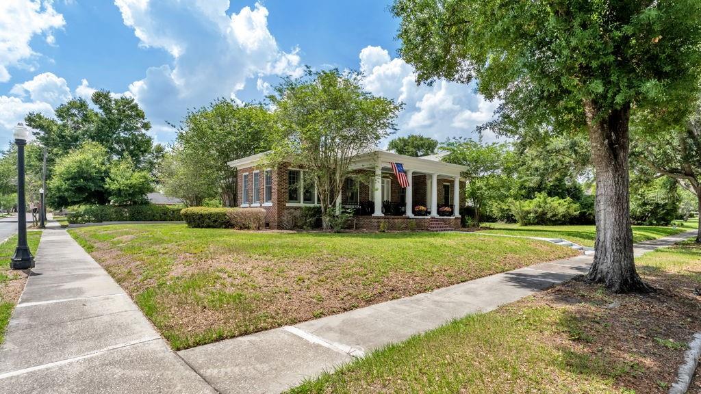 A single-story brick house with a front porch and an American flag stands on a lawn — 747 S CLAYTON AVENUE, LAKELAND, FL