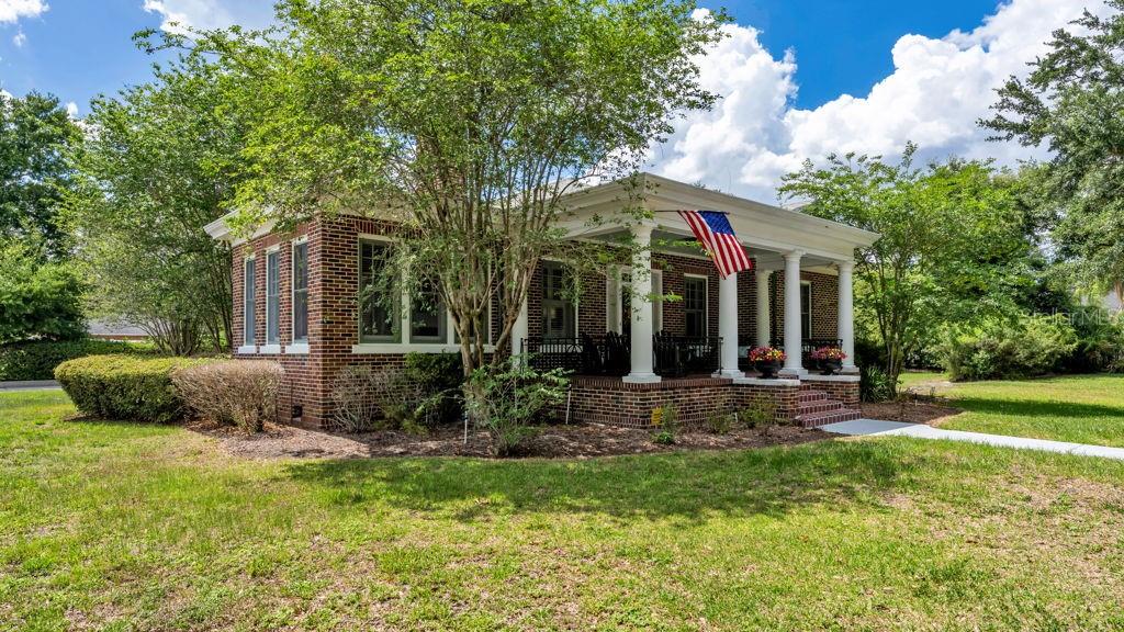 A brick house with a front porch and an American flag sits on a grassy lawn — 747 S CLAYTON AVENUE, LAKELAND, FL