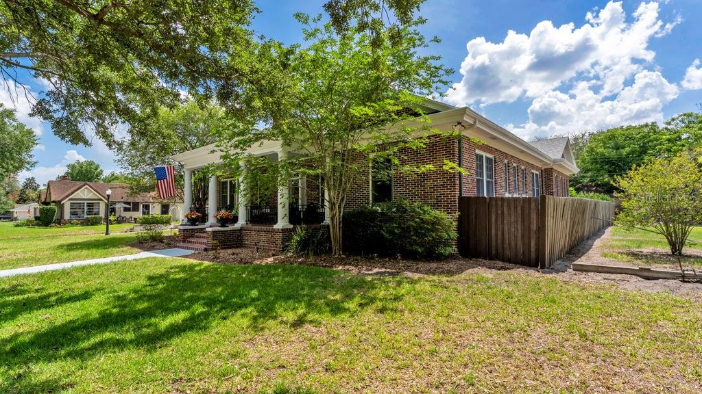 A brick house with a front porch and a wooden fence on a grassy lot — 747 S CLAYTON AVENUE, LAKELAND, FL
