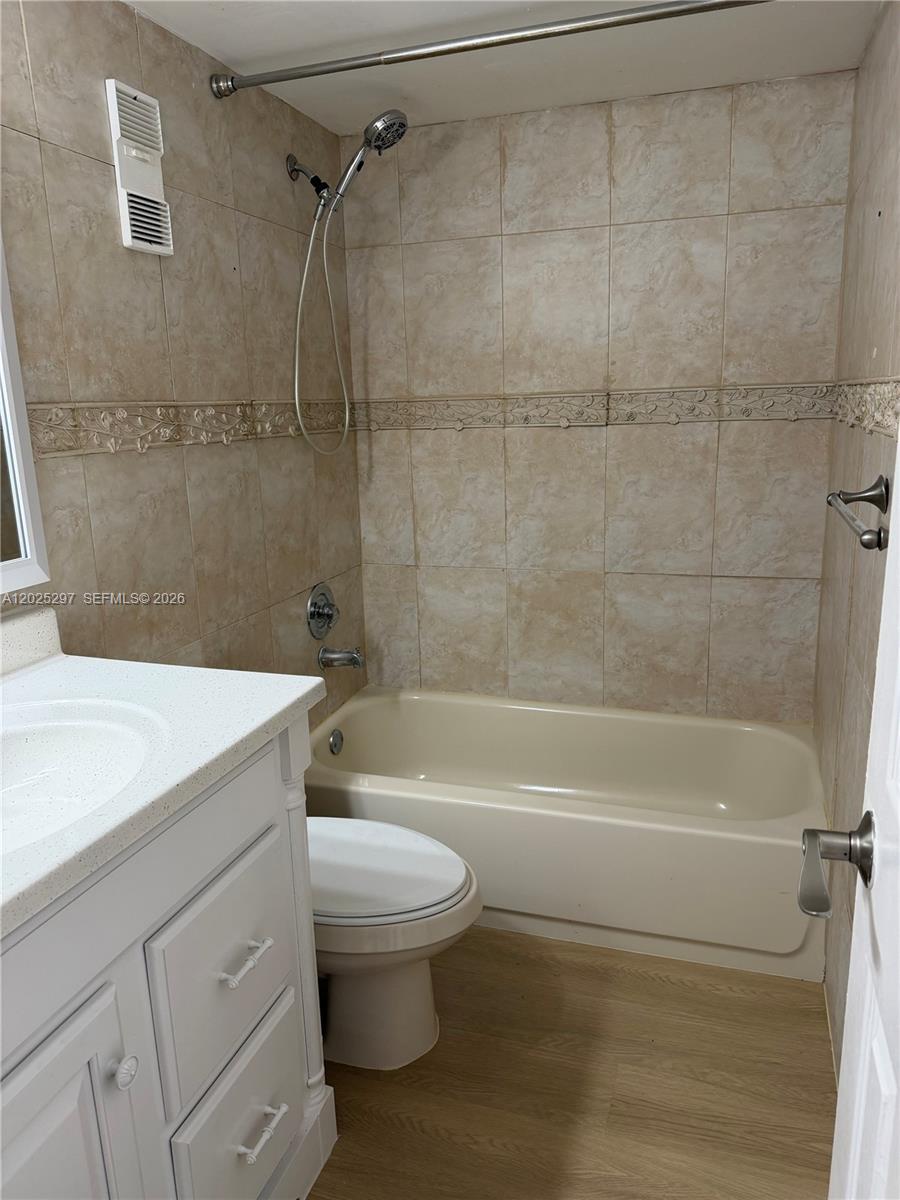 A bathroom features a white vanity, a toilet, and a beige bathtub with tiled walls — 8560 N Sherman Cir # 404, Miramar FL 33025, MIRAMAR, FL