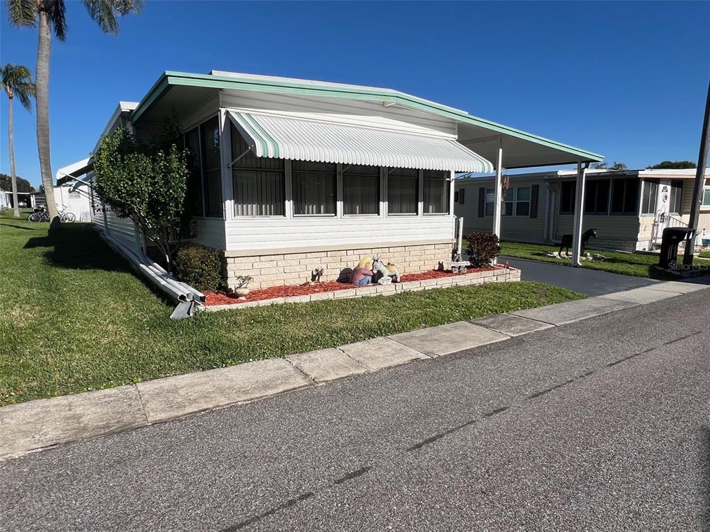 A single-story mobile home with a white metal awning and a brick-faced foundation — 29250 US HIGHWAY 19 N UNIT 135, CLEARWATER, FL