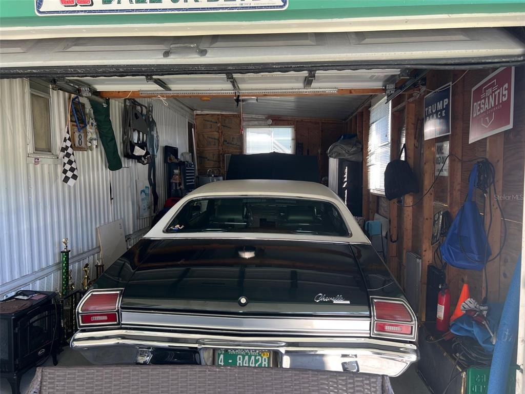 A classic black and white Chevelle is parked inside a cluttered residential garage — 29250 US HIGHWAY 19 N UNIT 135, CLEARWATER, FL