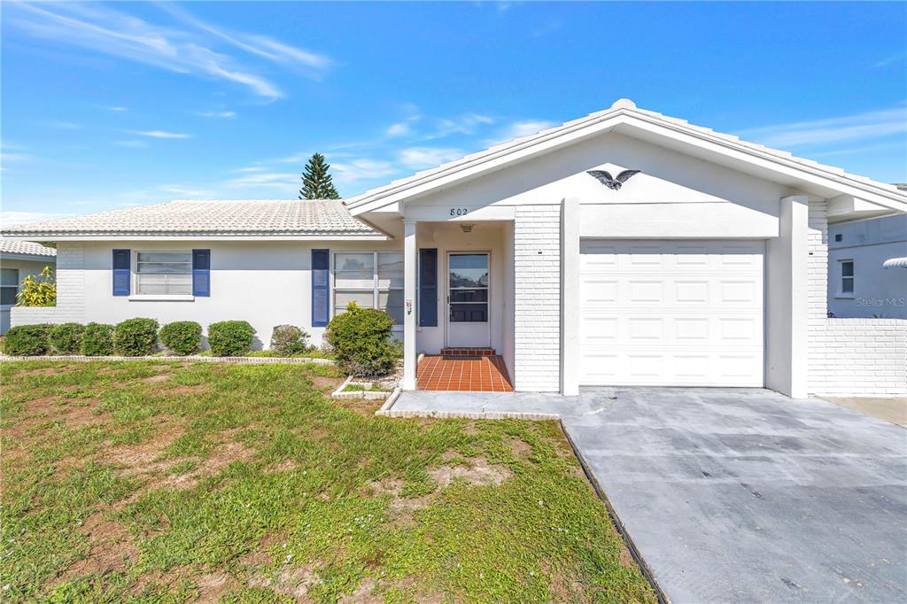 A white, single-story house with a garage, blue shutters, and a tiled entryway — 802 BUTTONWOOD DRIVE, BRADENTON, FL