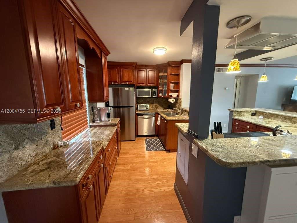 A kitchen features wood cabinets, granite countertops, stainless steel appliances, and hardwood flooring — 2691 S Course Dr # 202, Pompano Beach FL 33069, POMPANO BEACH, FL