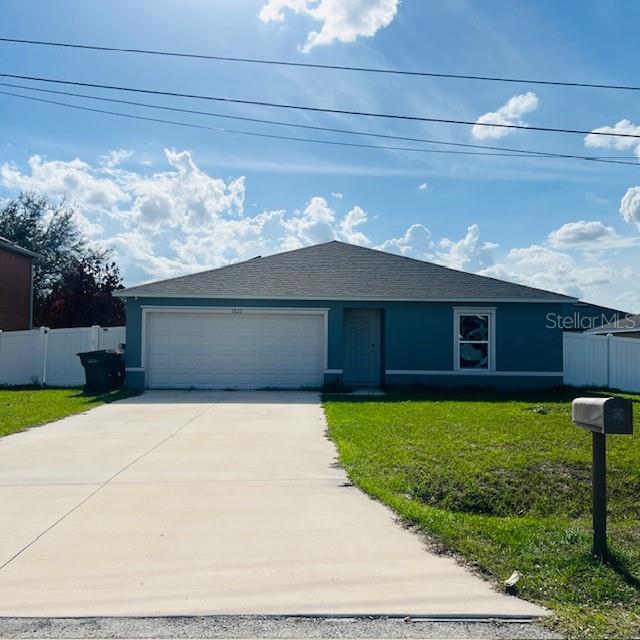 A teal single-story house features a two-car garage, a concrete driveway, and a white fence — 1822 BERING ROAD, KISSIMMEE, FL
