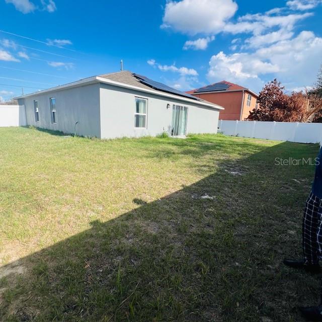 The exterior of a gray house with solar panels and a fenced backyard — 1822 BERING ROAD, KISSIMMEE, FL