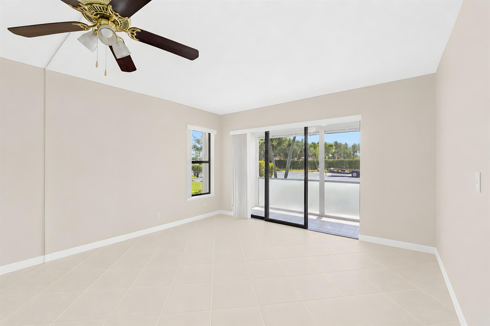 An empty room with beige tile flooring, a ceiling fan, and sliding glass patio doors — 821 Sky Pine Way # D1, FL 33415, FL