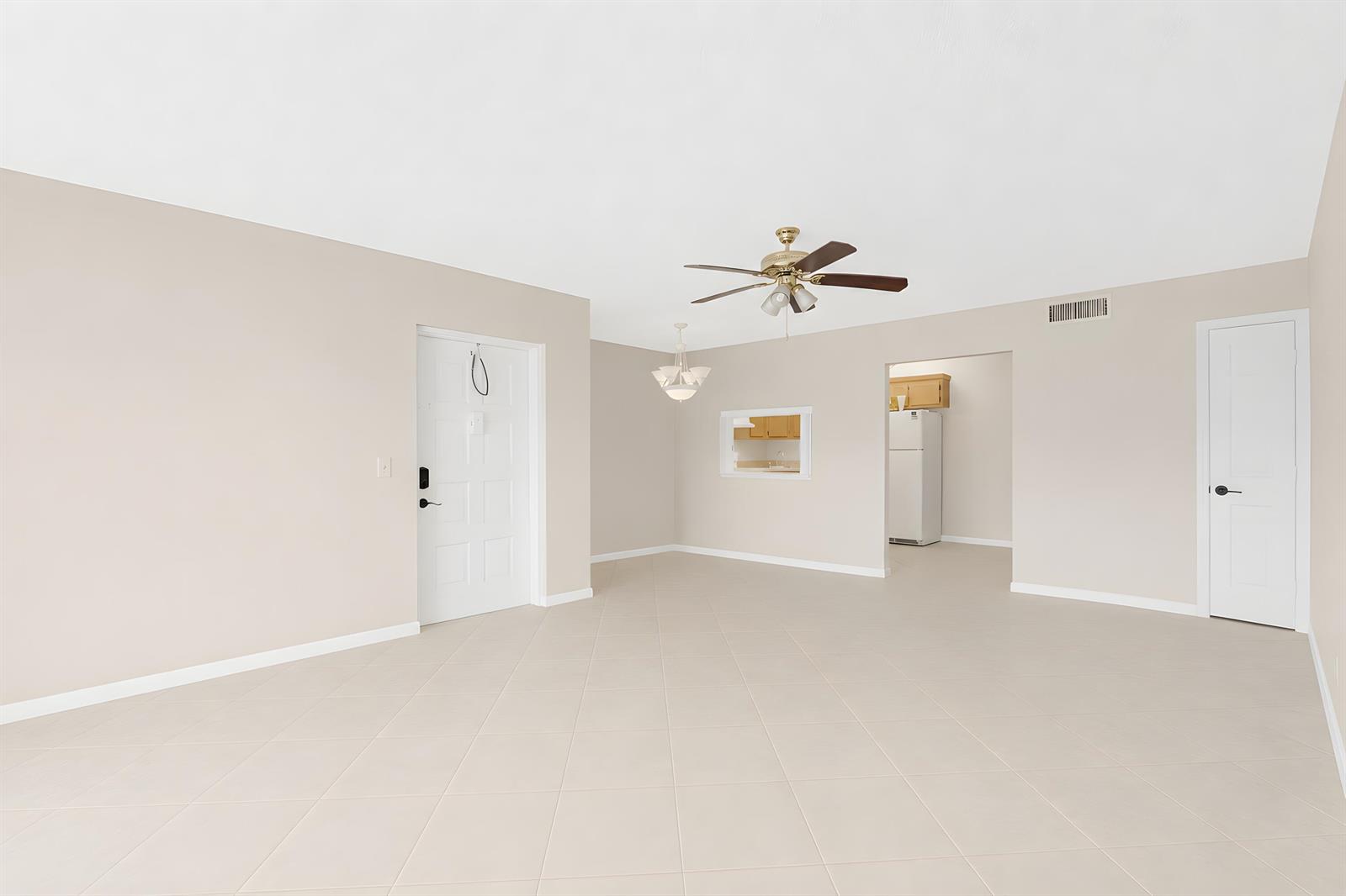 An empty room with beige tile flooring, a ceiling fan, and a white door — 821 Sky Pine Way # D1, FL 33415, FL