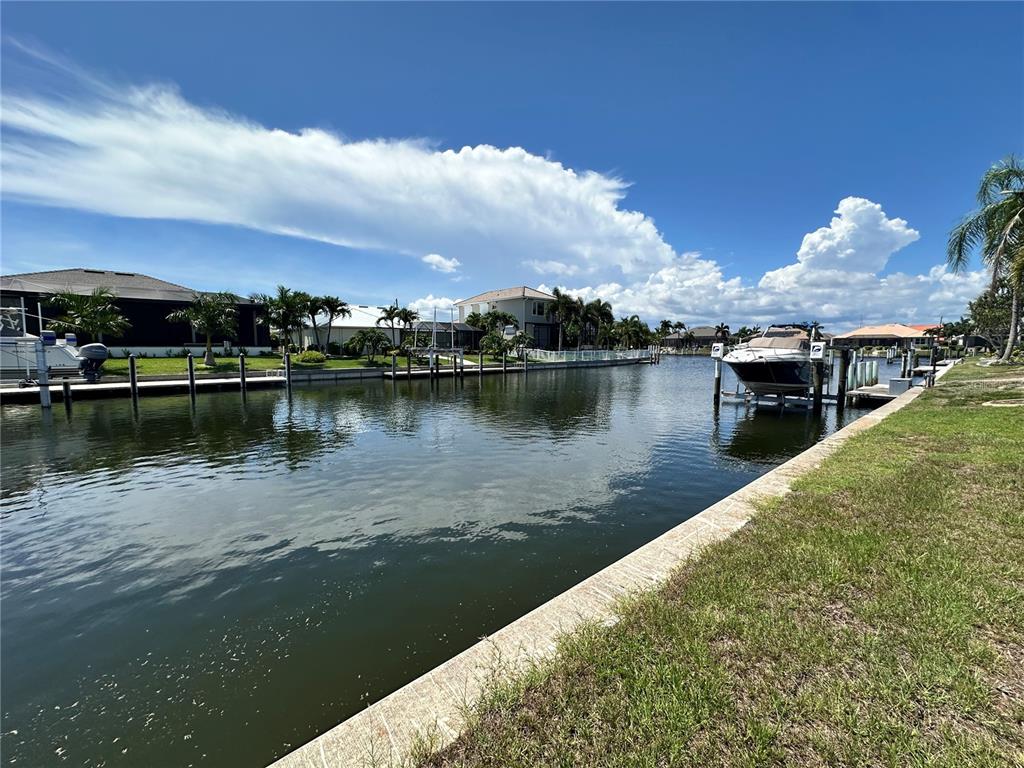 A canal view showing residential houses, boat docks, and a boat on a lift — 3611 BONAIRE COURT, PUNTA GORDA, FL