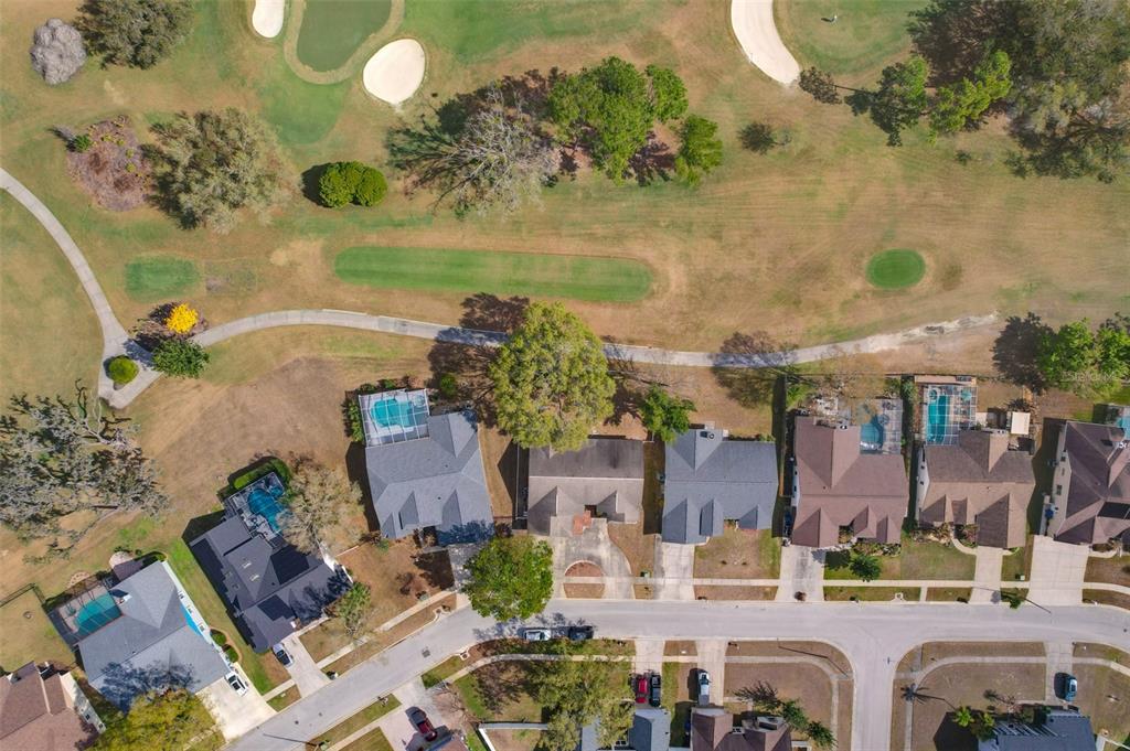 An aerial view shows several houses with swimming pools bordering a golf course and path — 2626 CRESTFIELD DRIVE, VALRICO, FL